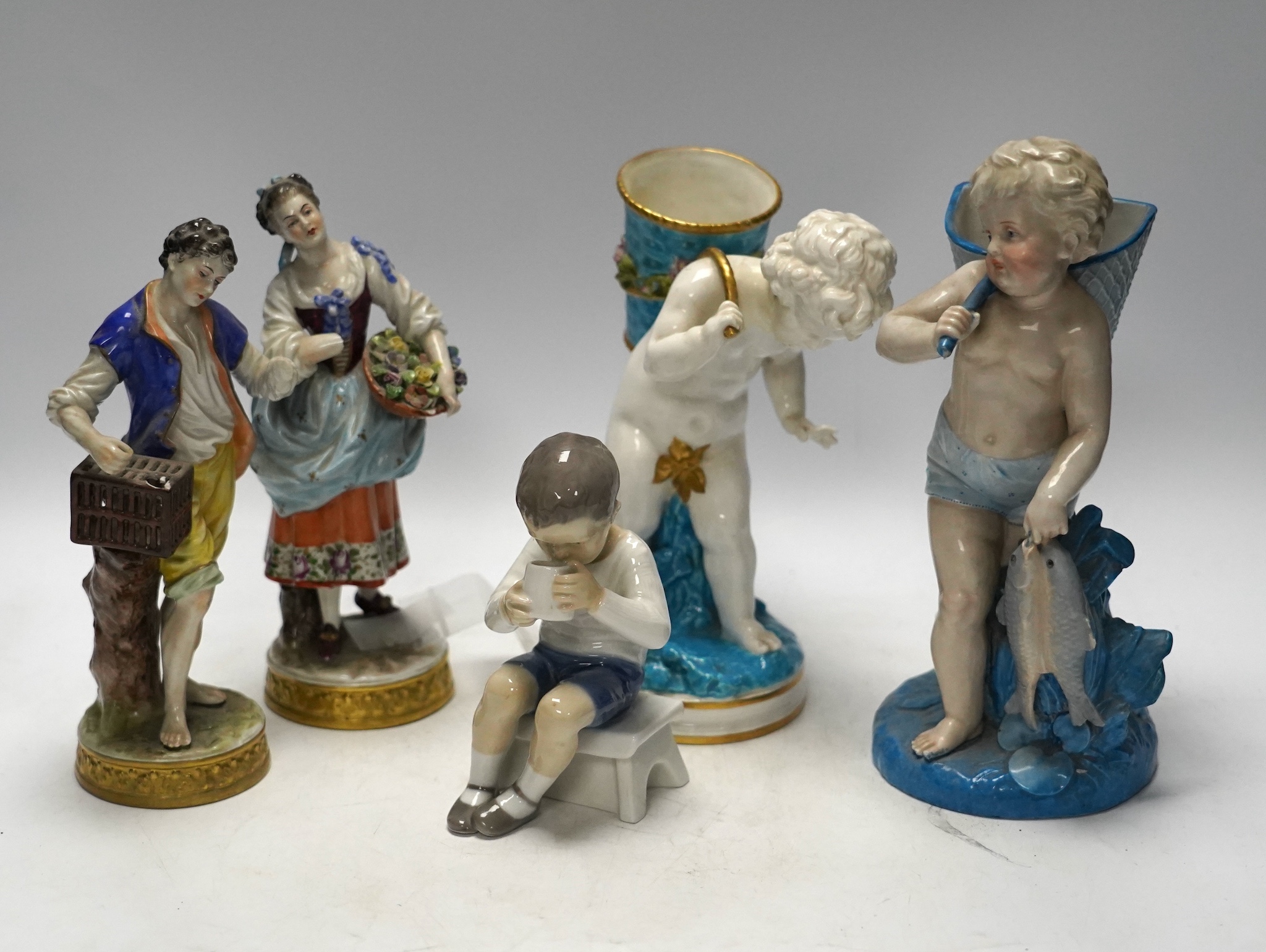 Three late 19th century porcelain putti spill vases and four smaller figurines, tallest 23cm high
